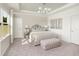 Elegant bedroom with tray ceiling, featuring neutral tones, a tufted bench, and natural light from a large window at 488 Village Ln, Fairburn, GA 30213