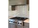 Close-up showcasing stainless steel stove, light grey cabinetry, white backsplash, and modern hardware in a designer kitchen at 4015 Sierra Vista Cir, Cumming, GA 30040