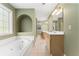 Bathroom featuring a bathtub, an arched ceiling niche, a double vanity, and tile floors at 4572 Mulberry Fields Ln, Auburn, GA 30011
