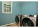 Modern laundry room with side by side silver washer and dryer, drying rack, tile floors and natural light at 4325 Acanthite Ct, Cumming, GA 30040