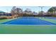 A tennis court featuring blue and green surface with net, benches, and surrounded by greenery at 4325 Acanthite Ct, Cumming, GA 30040