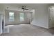 Bright living room features a ceiling fan, plush carpet, and staircase access at 64 Dogwood Rdg, Hampton, GA 30228