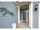 Covered front porch with decorative wall art, potted plants, and a security screen door at 109 Aspen Way, Dallas, GA 30157
