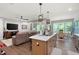 Open-concept kitchen with stainless steel appliances, island, pendant lighting and adjacent living room at 109 Aspen Way, Dallas, GA 30157