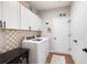 Neat laundry room with modern washer and dryer, white cabinets, black hardware and charming wall decor at 109 Aspen Way, Dallas, GA 30157
