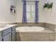 A soaking tub with tile surround and blue patterned window treatments at 3348 Perrington Pointe, Marietta, GA 30066