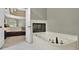 Bright bathroom featuring a soaking tub with fireplace and a connecting door to the bedroom at 9900 Hunt Club Way, Johns Creek, GA 30022