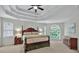 Comfortable main bedroom featuring a trey ceiling, ceiling fan and large windows at 9900 Hunt Club Way, Johns Creek, GA 30022