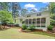 View of the backyard featuring a white brick home, screened porch, green grass, and mature trees at 1518 Rochelle Dr, Atlanta, GA 30338