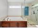 Bright bathroom featuring a soaking tub with a brown cabinet and walk-in shower with glass door at 725 Eider Down Ct, Alpharetta, GA 30022