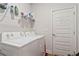 The laundry room has a white door, a washer, a dryer, and a wire shelf at 8268 E Carroll Rd, Whitesburg, GA 30185