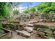 Landscaped backyard with a raised garden, stone retaining wall, and rock steps at 2490 Hillandale Cir, Cumming, GA 30041