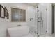 Bright bathroom featuring a soaking tub, seamless glass shower, and marble tile at 2490 Hillandale Cir, Cumming, GA 30041