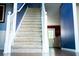 Carpeted staircase with white railing, leading to a home's upper level, with hardwood floors in the foyer at 4041 Smithfield Trl, Ellenwood, GA 30294