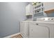 Bright laundry room features modern washer and dryer units, wall-mounted storage shelf, and cabinets at 241 Irwell Path, Lawrenceville, GA 30044