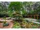 Lush backyard with a stream, stone bridge, manicured landscaping and a wooden pergola at 5120 Jett Forest Trl, Atlanta, GA 30327
