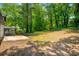 Spacious backyard with a concrete patio, mature trees, and partial view of the sunroom at 157 Jousters Ln, Lawrenceville, GA 30044