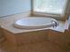 Bathroom showcasing tiled tub and window with blinds at 3943 Dunaire Dr, Stone Mountain, GA 30083