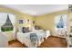 Charming yellow bedroom with hardwood floors, featuring two twin beds with white linens and decorative pillows, and natural light at 4716 N Springs Ct, Atlanta, GA 30338