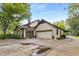 Exterior view of a home featuring a large driveway, attached garage, and lush landscaping, showcasing curb appeal at 4716 N Springs Ct, Atlanta, GA 30338
