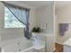 Bright bathroom featuring a soaking tub under a large window and white tiled surround at 900 Meadowsong Cir, Lawrenceville, GA 30043