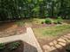 Landscaped backyard with brick walkway leading to wooden steps and mature trees at 5755 Hendrix Rd, Cumming, GA 30040