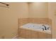 Tiled corner bathtub with tile surround in neutral-toned bathroom at 5755 Hendrix Rd, Cumming, GA 30040