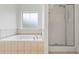 Elegant bathtub with tile surround next to a glass shower and window, providing a relaxing oasis at 4368 Magnolia Bay Ln, Snellville, GA 30039