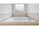 Close-up of an elegant built-in bathtub with tile surround next to a frosted window at 4368 Magnolia Bay Ln, Snellville, GA 30039