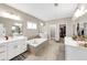 Spa-like bathroom with double vanities, a soaking tub, and modern fixtures at 5075 Briarstone Ridge Way, Alpharetta, GA 30022