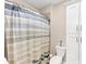 Bathroom features a tub with a shower curtain, white toilet and storage cabinet at 5075 Briarstone Ridge Way, Alpharetta, GA 30022