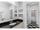 Stylish bathroom featuring black granite counters, built-in shelving, and black-and-white tile flooring at 2109 Rugby Ave, Atlanta, GA 30337