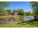 A lush backyard featuring a tranquil lake with a fountain, surrounded by mature trees and manicured lawns at 6185 Deerwoods Trl, Alpharetta, GA 30005