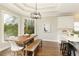 Sunlit dining area boasts a rustic wooden table, modern light fixture, and views of the water at 6185 Deerwoods Trl, Alpharetta, GA 30005