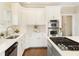 Well-appointed kitchen features white cabinets, stainless steel appliances, and stone countertops at 6185 Deerwoods Trl, Alpharetta, GA 30005