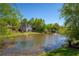 Exterior view of the home and pond, with manicured lawn and mature trees at 6185 Deerwoods Trl, Alpharetta, GA 30005