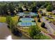 Aerial view of multiple tennis courts with a lake and clubhouse at 6185 Deerwoods Trl, Alpharetta, GA 30005