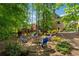 Landscaped backyard with a fire pit, seating, mature trees, and a play structure at 320 Rossiter Rdg, Alpharetta, GA 30022