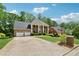 Stately brick home with a long driveway, large garage, mature trees, and manicured lawn at 320 Rossiter Rdg, Alpharetta, GA 30022