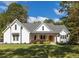 Beautiful two-story white home with a lush green lawn and lovely front porch, offering great curb appeal at 9770 Coleman Rd, Roswell, GA 30075