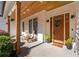 Inviting front porch with wood columns, rocking chairs, hanging plants, and a stylish wood front door at 9770 Coleman Rd, Roswell, GA 30075