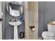 Stylish powder room featuring pedestal sink, wooden accent panel, and a modern round mirror at 1386 Ben Park Way, Grayson, GA 30017