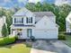 Charming two-story home featuring a manicured lawn, flowering plants, and a welcoming two-car garage at 338 Santa Anita Ave, Woodstock, GA 30189