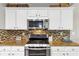 Updated kitchen featuring white cabinets, stainless steel appliances, and decorative tile backsplash at 338 Santa Anita Ave, Woodstock, GA 30189