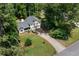 Aerial view of home featuring a front porch, two-car garage, lush green lawn, and surrounding trees at 83 Andrew Jackson Ct, Dallas, GA 30157