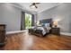 Comfortable bedroom features a ceiling fan, large window, stylish bed with wood frame and hardwood flooring at 1101 N Flat Rock Rd, Douglasville, GA 30134