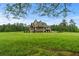 Expansive lush green lawn extends behind a two-story home with stone and wood accents and covered veranda at 1101 N Flat Rock Rd, Douglasville, GA 30134