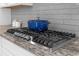 Close-up of a gas cooktop with granite countertops, tiled backsplash, and a blue pot at 319 Parkside Meadow Dr, Marietta, GA 30064