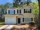 Charming two-story home featuring light yellow siding, a garage and a cozy front yard with trees at 4510 Swan Trce, Atlanta, GA 30349
