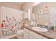 Well-lit bathroom with floral shower curtain, white cabinets, and framed wall decor at 660 Delbridge Nw St, Atlanta, GA 30314